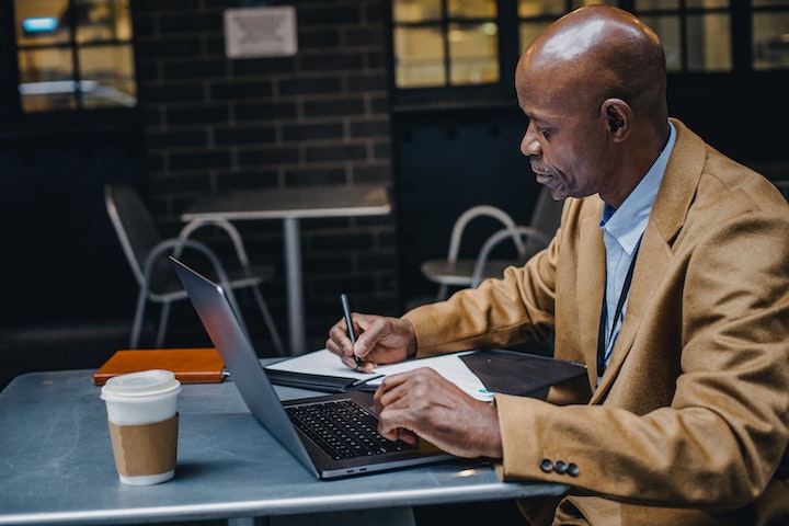 Image of a man studying on a laptop in a cafe.