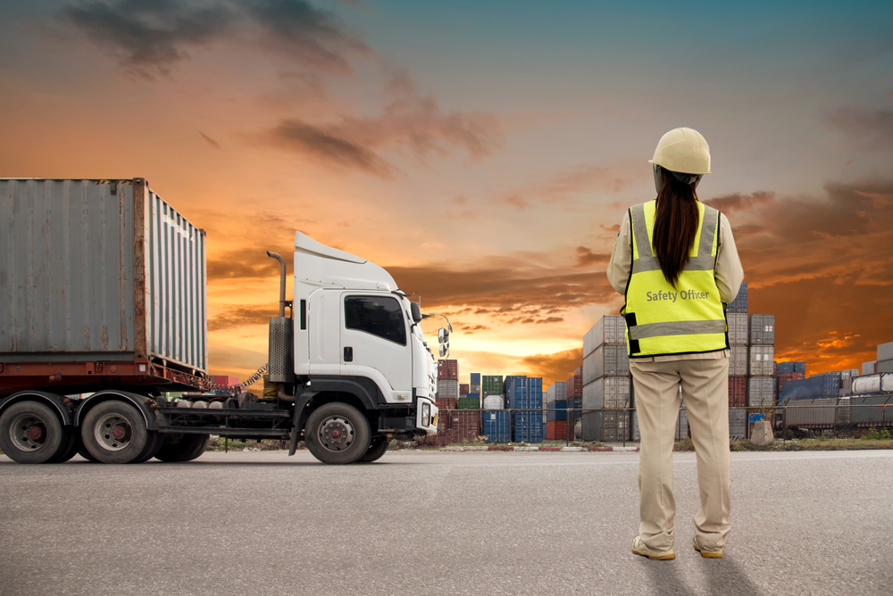 woman standing next to truck and shipping containers